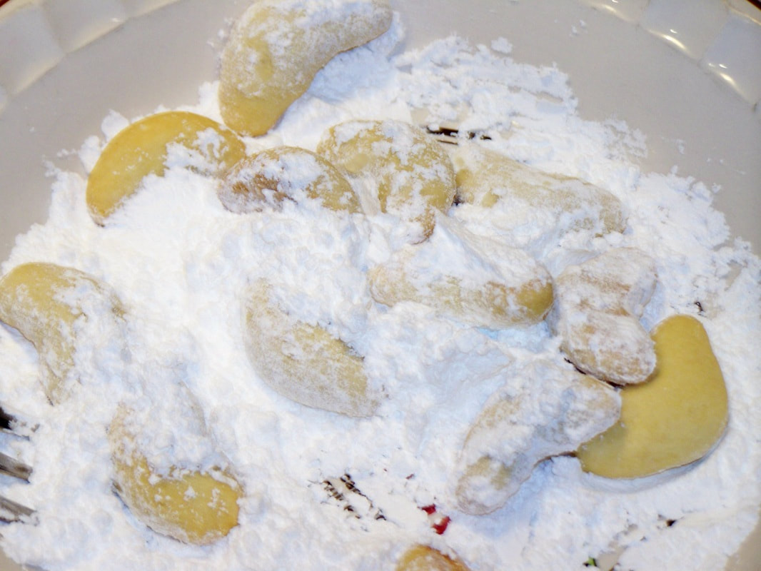 Coat cooled Greek cookies with powdered sugar